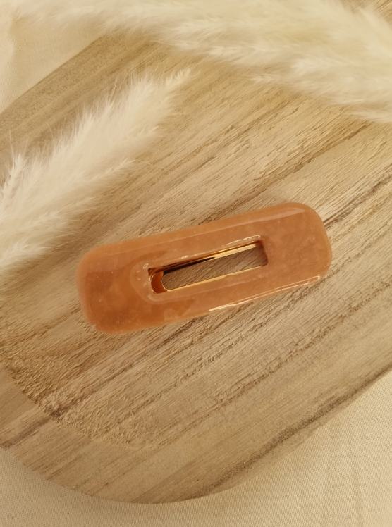 Barrette de forme rectangulaire posée sur un support en bois. Faite main en argile polymère et en acier inoxydable. Ton beige opale. Modèle Barrette Rectangulaire, style classique.