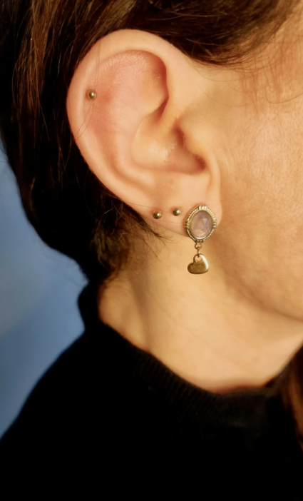 Boucles d'oreilles en forme d'oeuf, avec un petit coeur accroché. Faites main en améthyste et en acier inoxydable. Portées par la créatrice. Tons mauve et doré. Modèle Anémone, style classique et romantique.