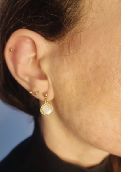 Boucles d'oreilles en forme de sphère. Faites main en nacre et en acier inoxydable. Portées par la créatrice. Tons blanc et doré. Modèle Anthéa, style classique.